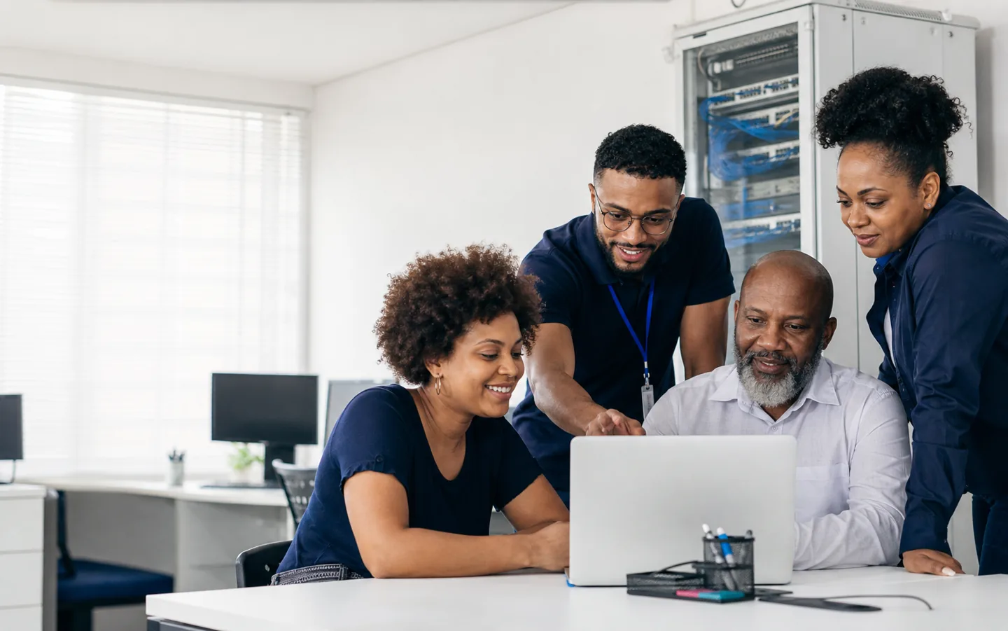 Equipe diversa de tecnologia da UPTECH colaborando com um cliente em um computador